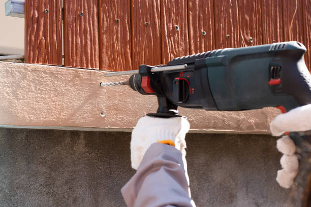 Man hand holding and using electric drill at cement wall. Maintenance concept. Man hand holding and using electric drill at cement wall. Maintenance concept.