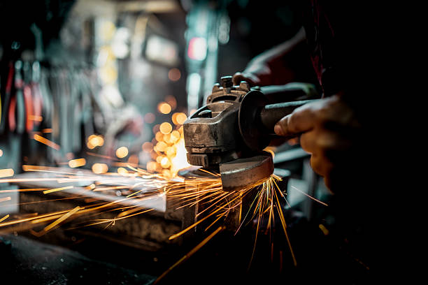 An individual uses a grinding tool on a metal surface with sparks flying in the process, creating a workshop atmosphere.