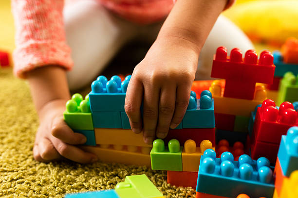Close-up of little girl building something with plastic blocks on the floor. Close-up of little girl building something with plastic blocks on the floor.
